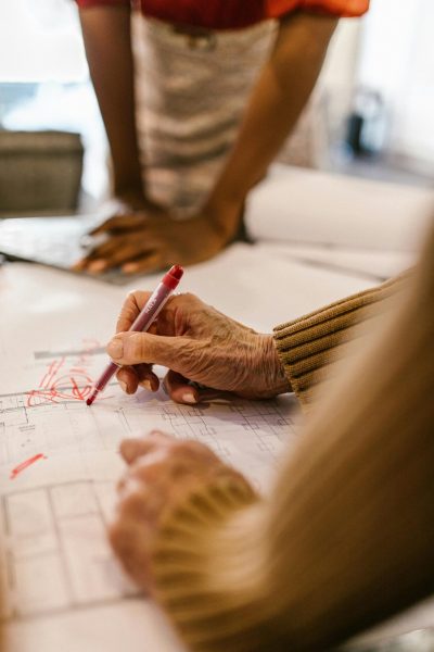 Hands working on office blueprints during a collaborative business meeting.